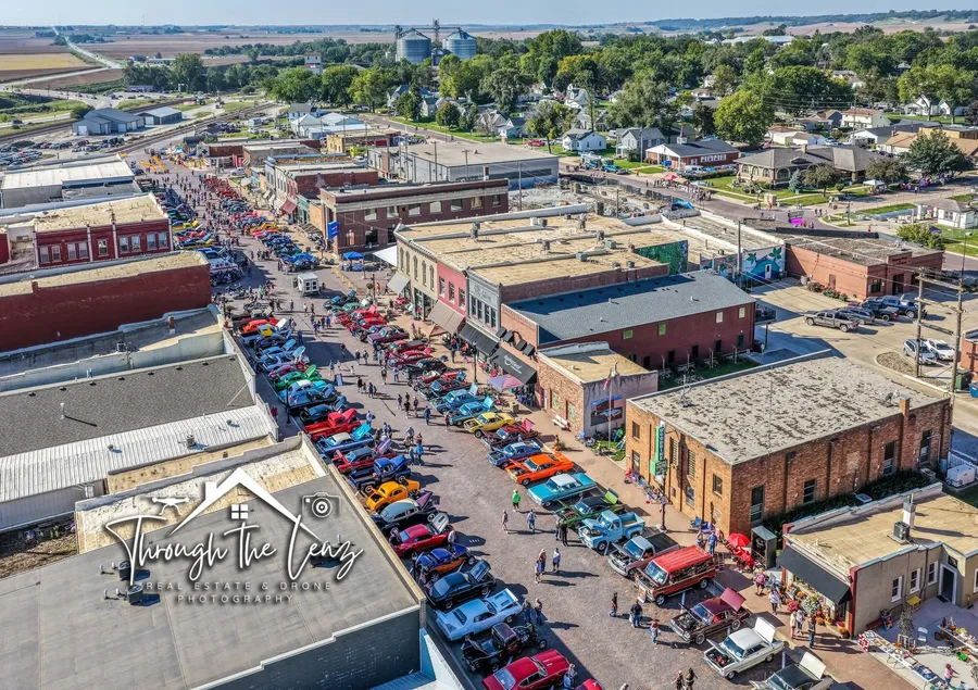 Aerial view of a small-town street festival and classic car show lined with vehicles and crowds
