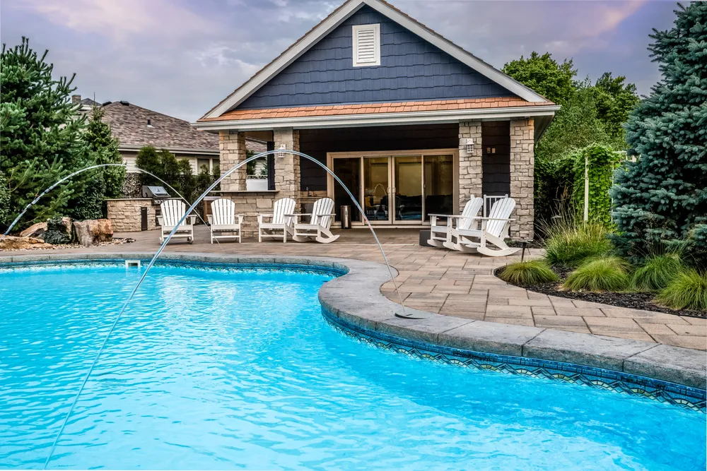 Twilight view of a home with a lit backyard pool
