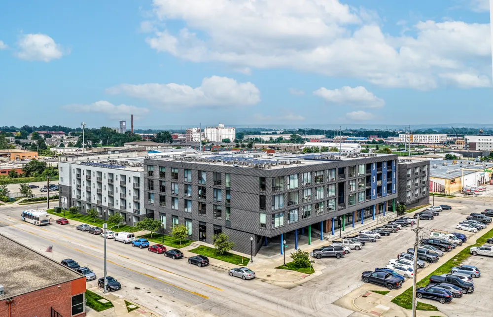 Aerial view of a multifamily apartment building with an industrial cityscape backdrop