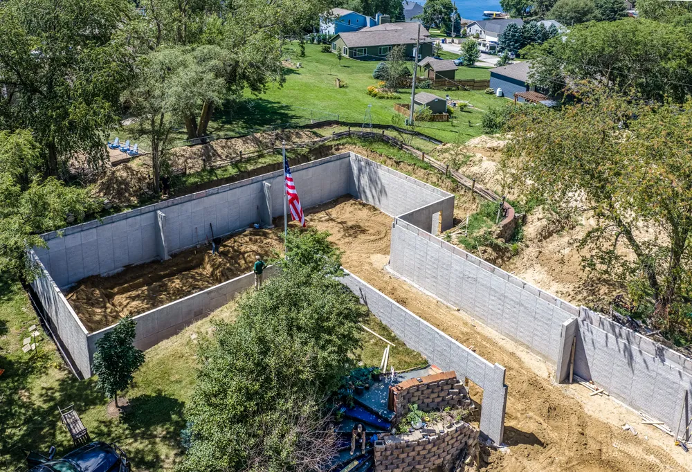 Aerial view of a poured foundation for a new home under construction near a lake