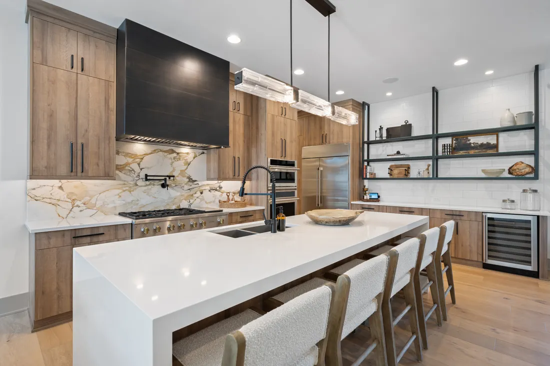A modern kitchen with a waterfall marble island and open wood shelving