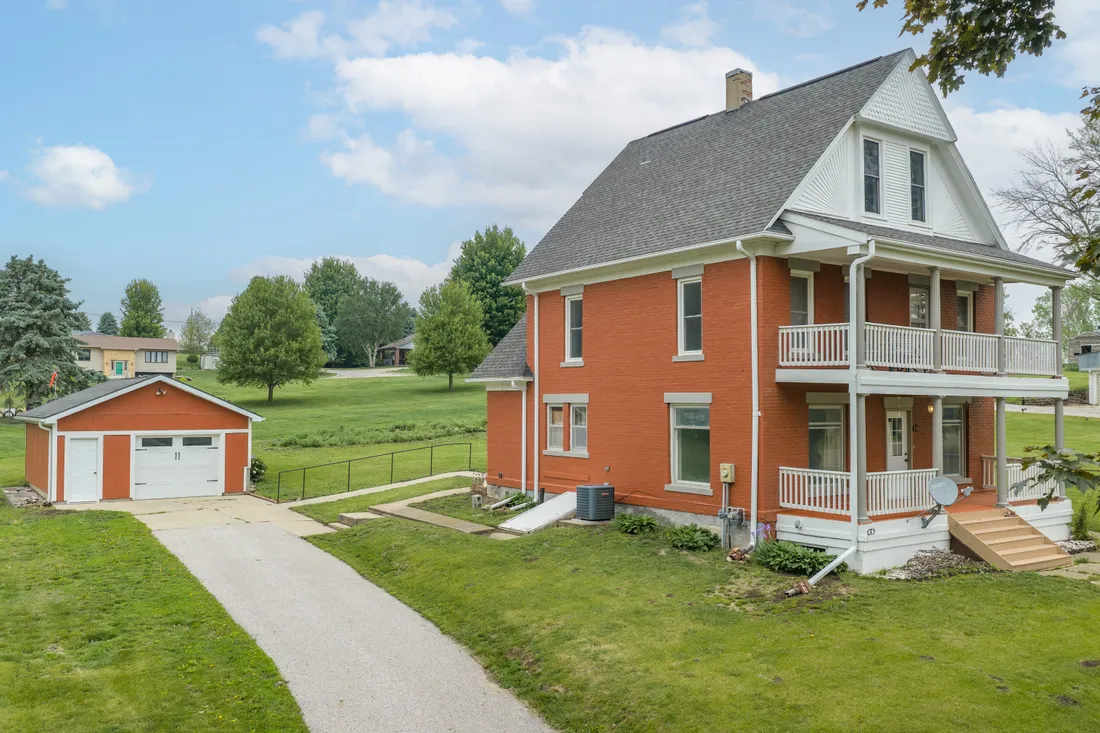 Aerial view of a two-story brick home with a wraparound porch