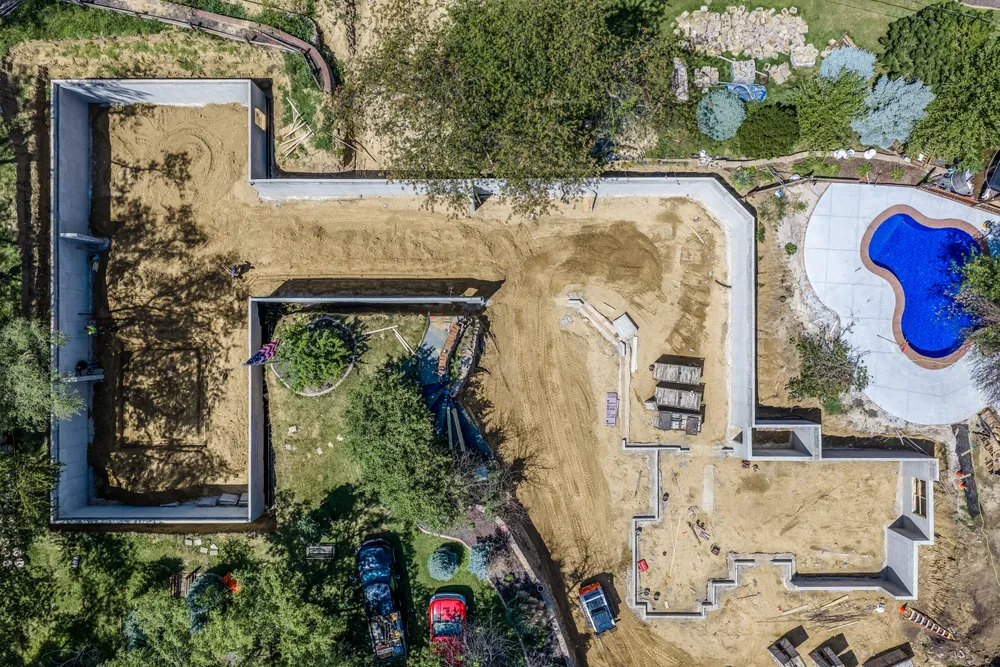 Straight-down aerial view of a home under construction with an in-ground pool being built