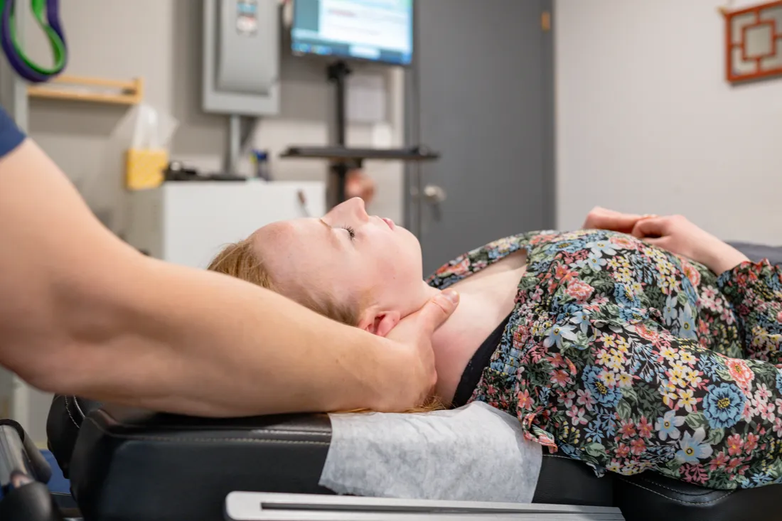 A chiropractor treating a patient in a clinic exam room