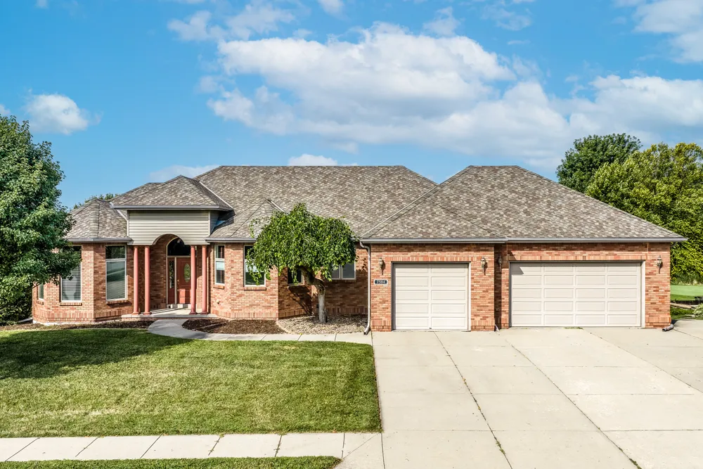 Aerial view of a brick ranch home with a circular driveway