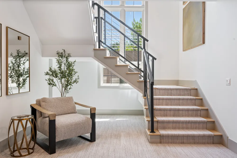 A modern open staircase with cable railing beside a tall window
