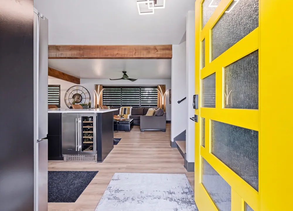 A bold yellow front door opening onto a modern open-concept kitchen and living space