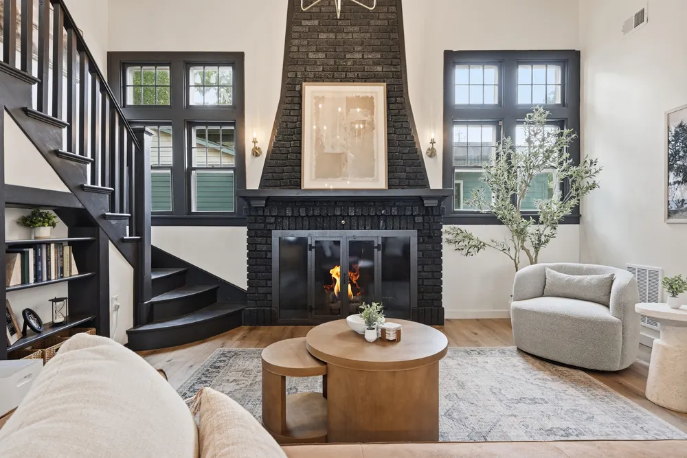 A living room with a tall black brick fireplace and vaulted ceiling